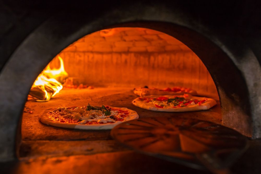Three Pizzas Are Being Cooked in a Wood Fired Pizza Oven — Mumbo's Pizza'n'Pasta In Lismore, NSW