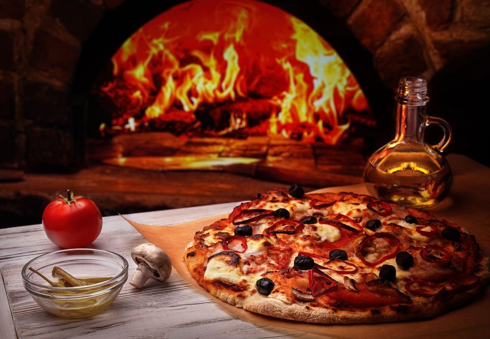 A Pizza is Sitting on a Table in Front of a Pizza Oven — Mumbo's Pizza'n'Pasta In Lismore, NSW