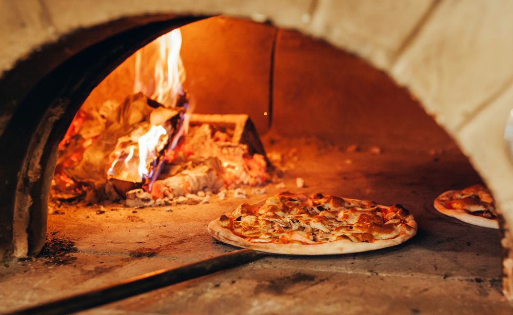 A Pizza is Being Cooked in a Wood Fired Oven — Mumbo's Pizza'n'Pasta In Lismore, NSW