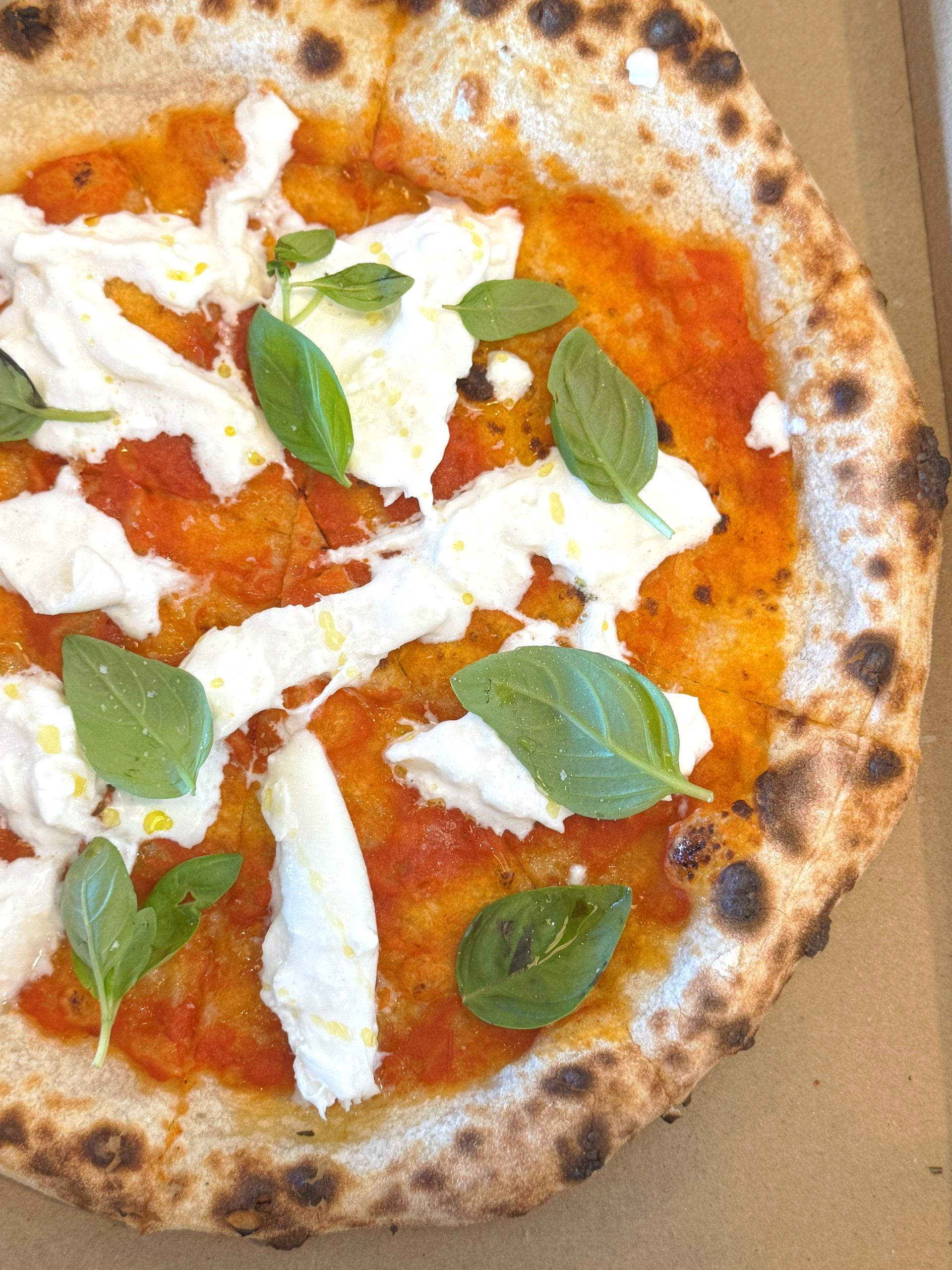 A Pizza Is Sitting On A Wooden Cutting Board On A Wooden Table — Mumbo's Pizza'n'Pasta In Lismore, NSW