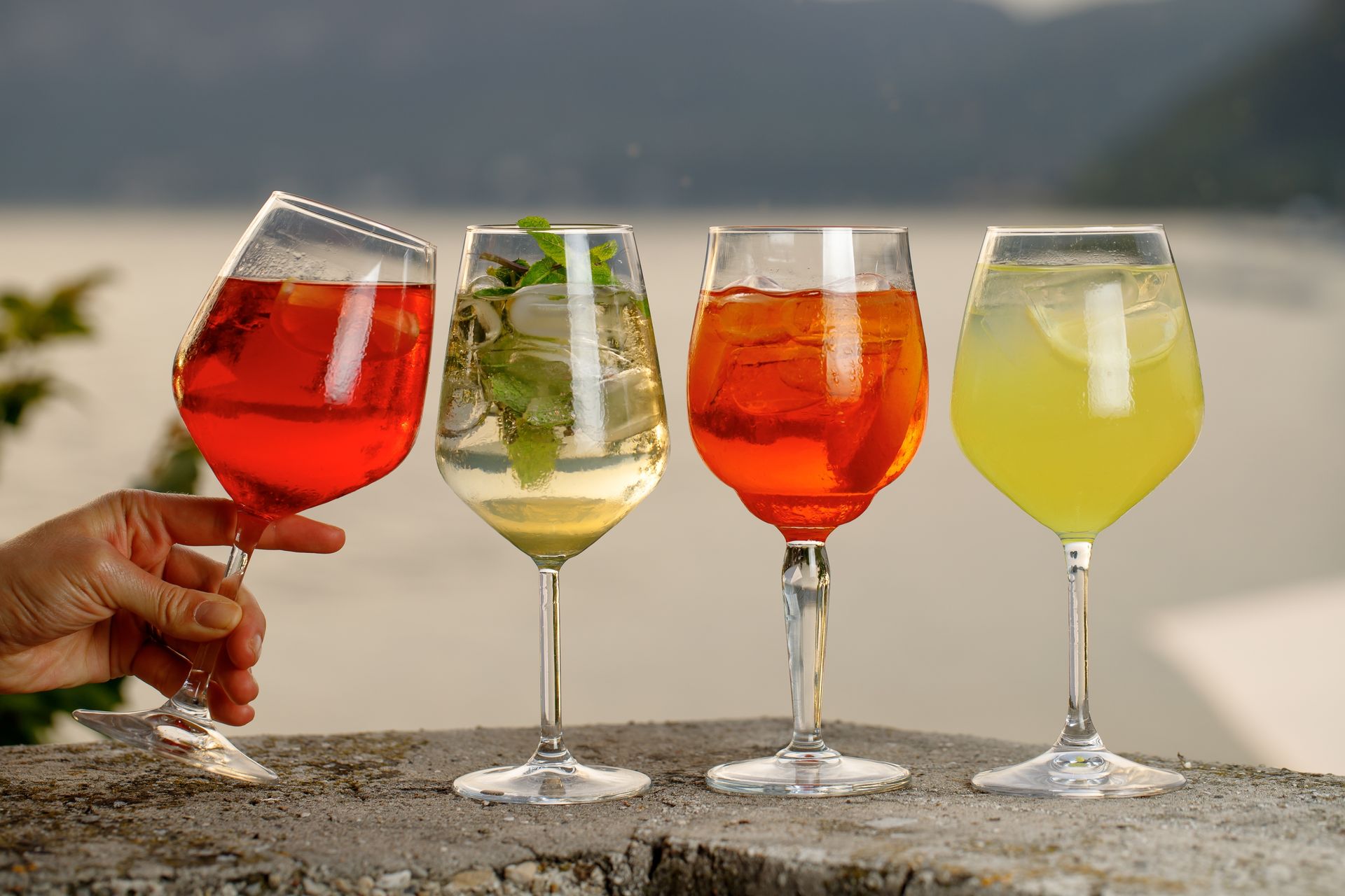 A Person is Holding Four Wine Glasses With Different Drinks in Them — Mumbo's Pizza'n'Pasta In Lismore, NSW