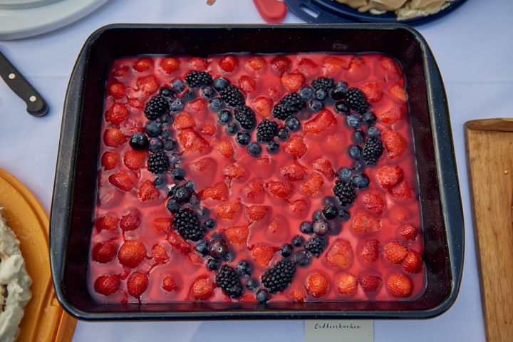 Hochzeitstorte mit einem Herzen aus Beeren. Aufgenommen auf einer Hochzeit in Brandenburg von dem Berliner Hochzeitsfotografen.