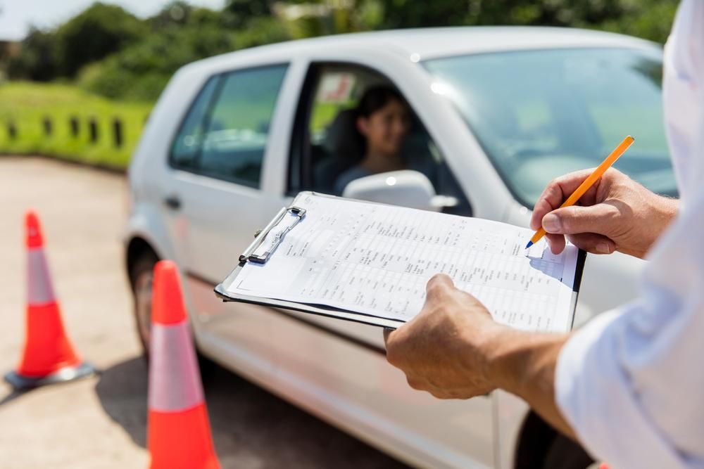 A Man with a checklist form with a woman in the driving seat of a car — Primera Driving School Darwin In Anula, NT