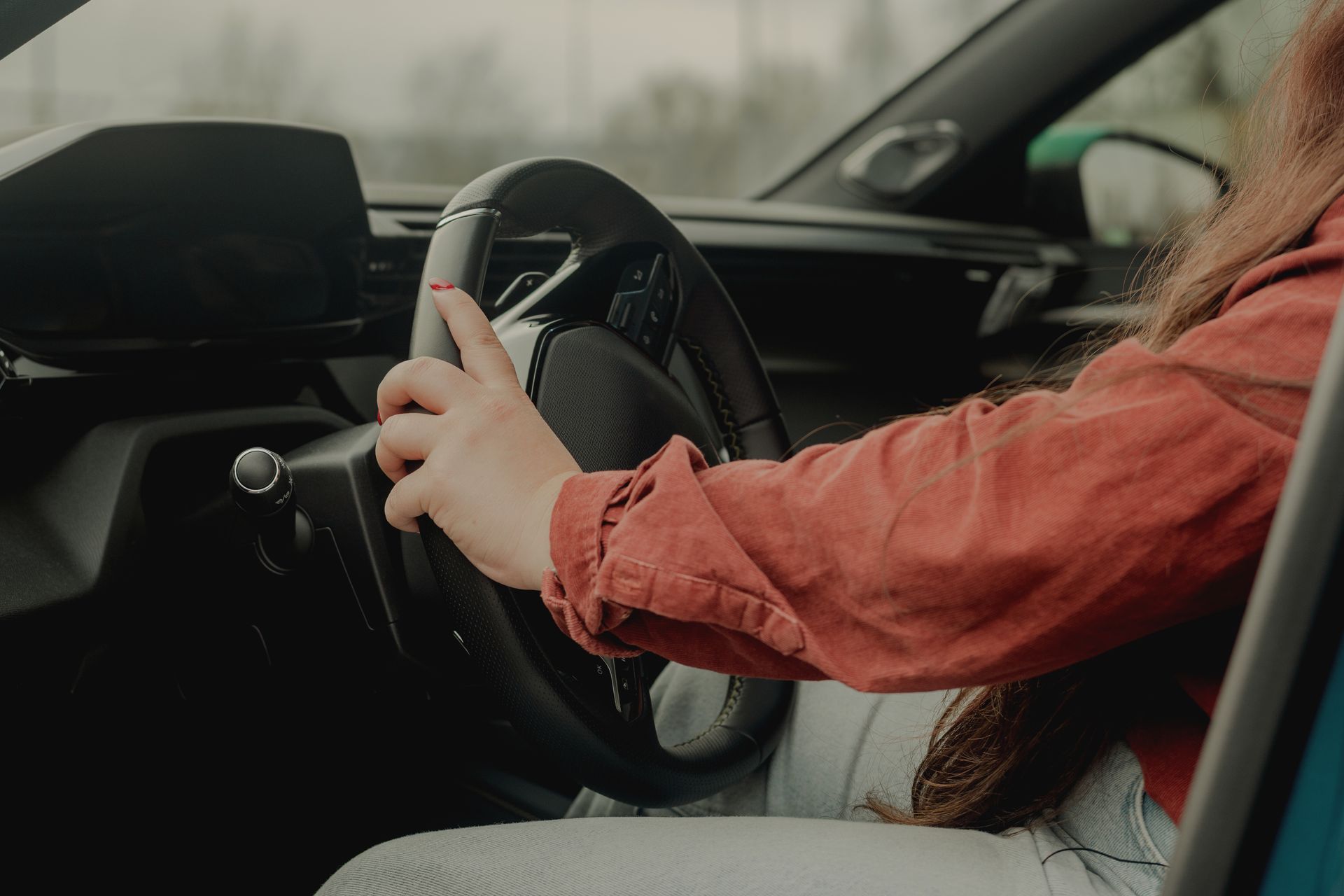 Female hands-on steering wheel in modern car interior.