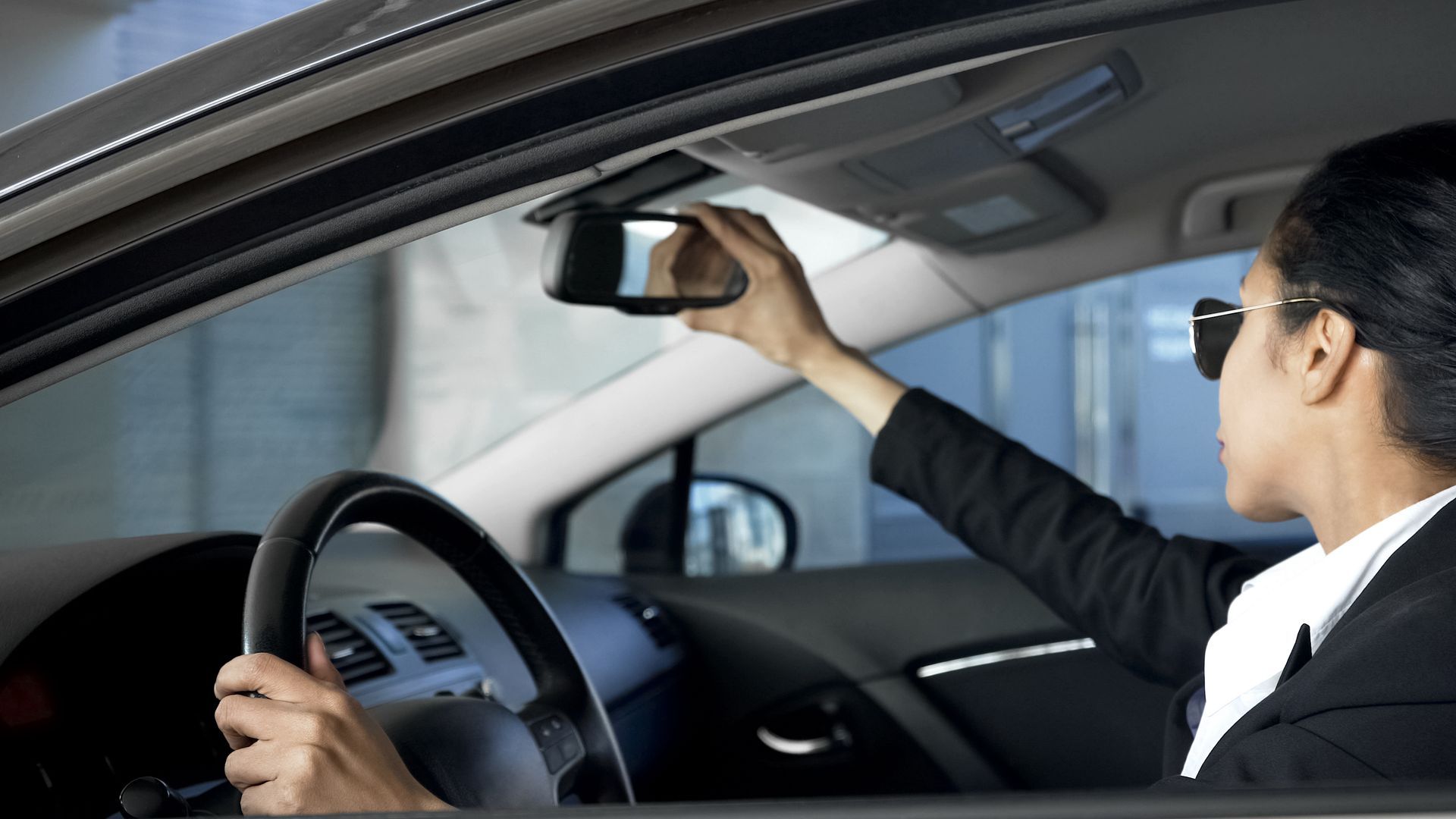 Person in a car looking at the rear view mirror.