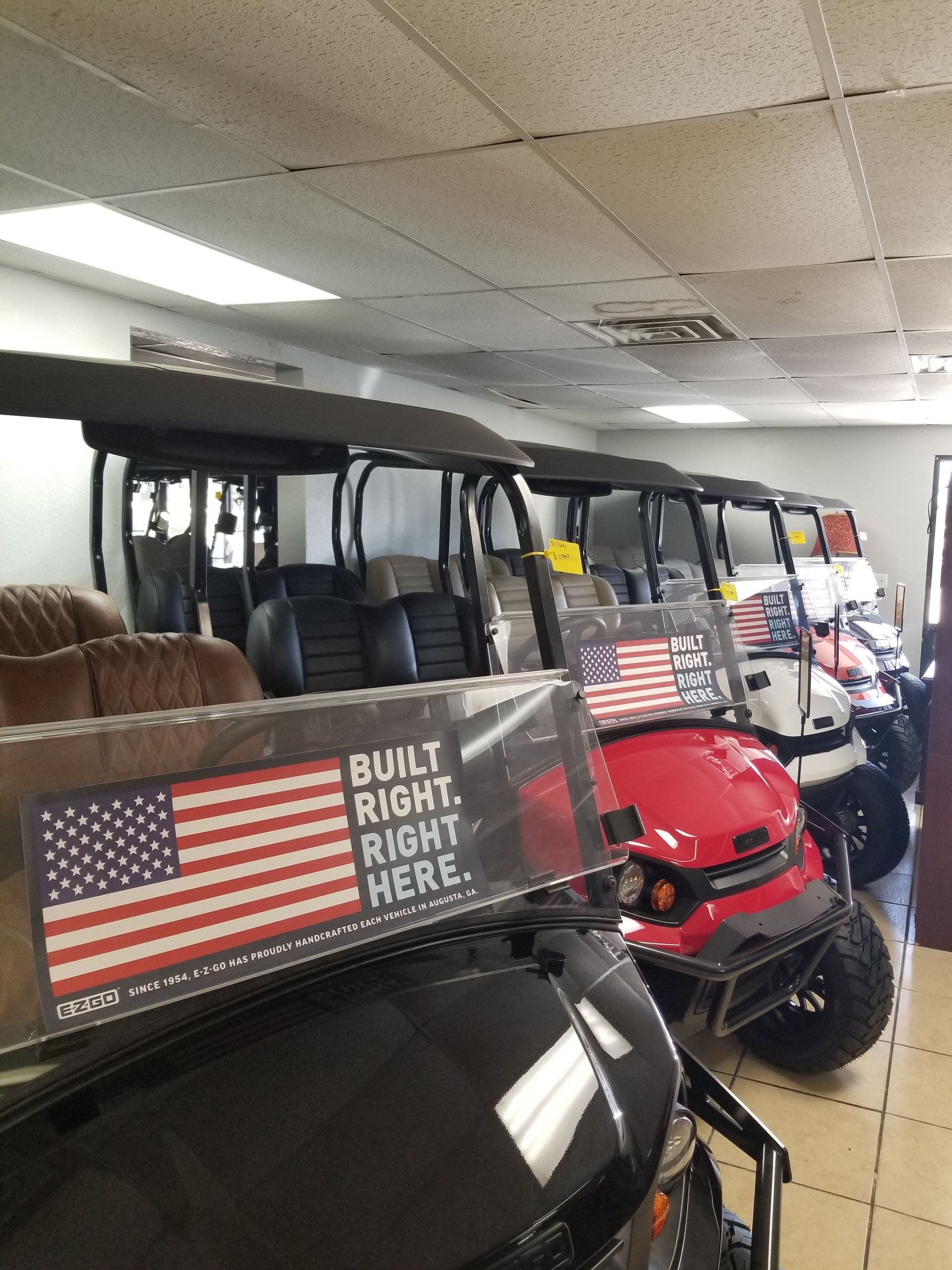 A row of golf carts are lined up in a showroom.