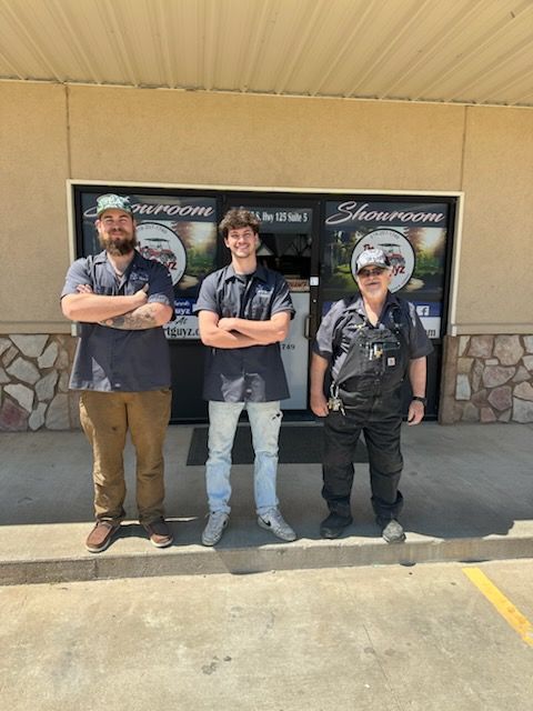 Three men are standing in front of a building with their arms crossed.