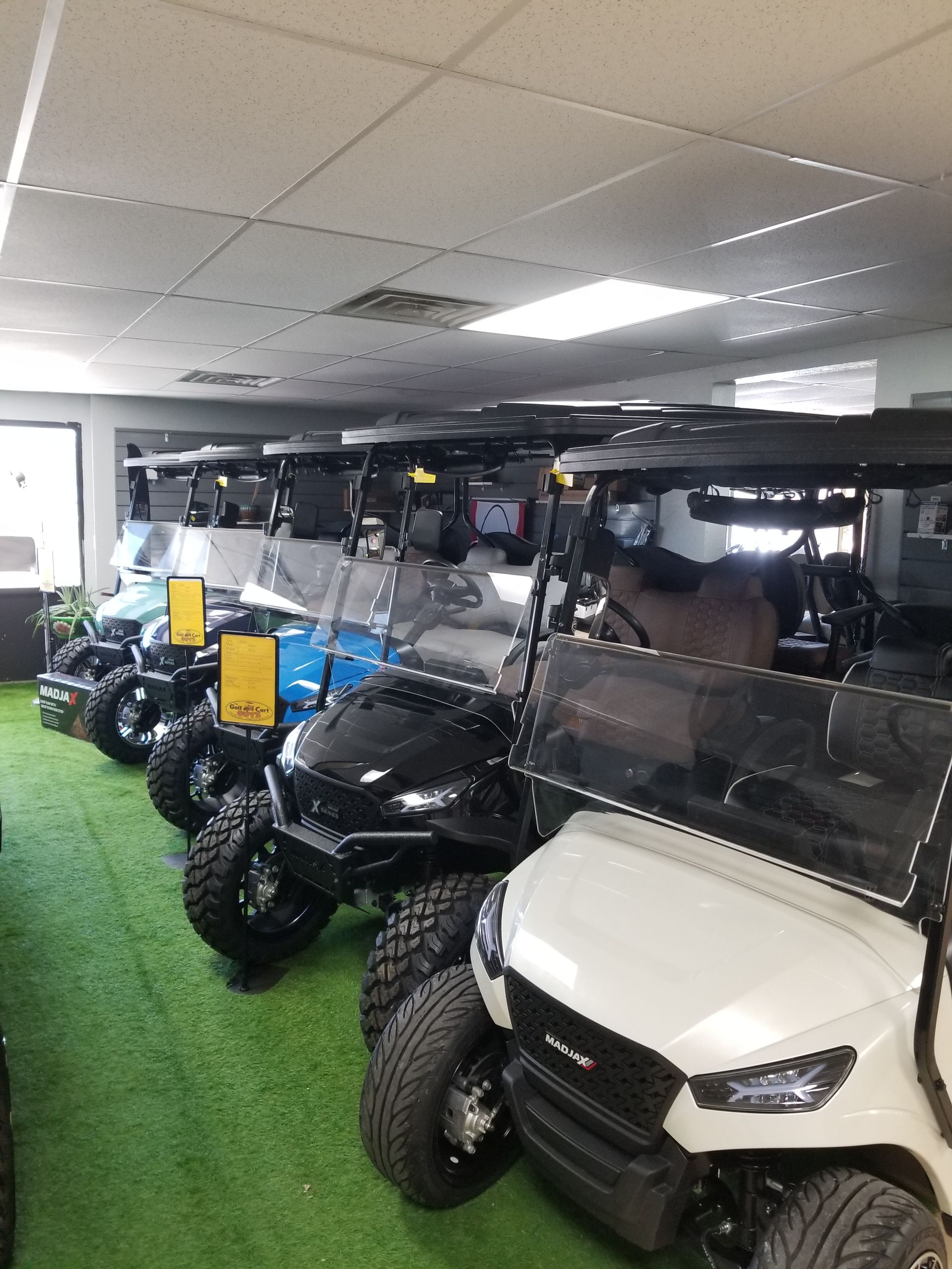 A row of golf carts are lined up in a showroom.