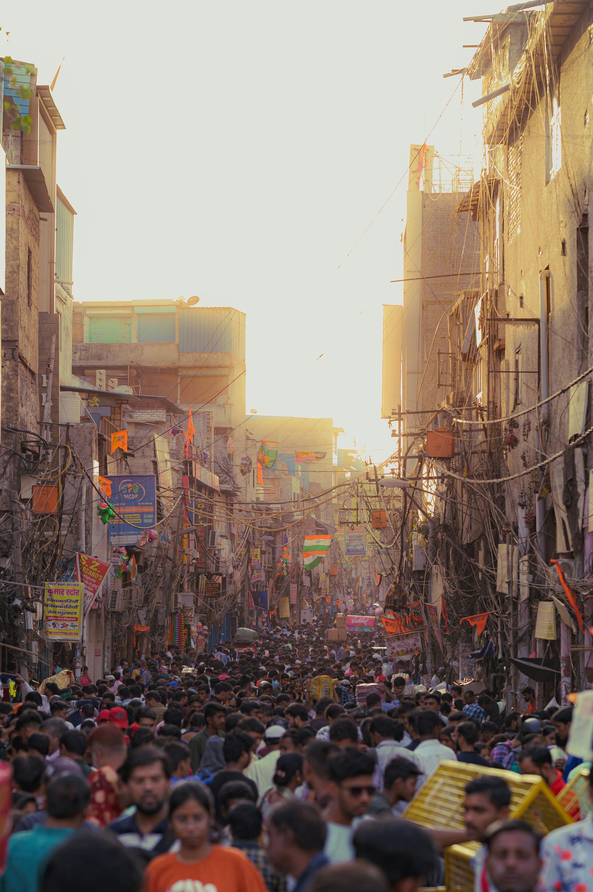 Bustling street in Old Delhi with flags and wires, representing historical landmarks like Red Fort and Chandni Chowk
