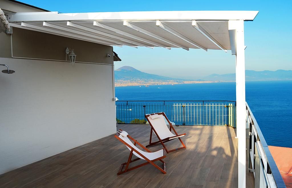 Un pergolato grigio scuro illuminato, attaccato a un muro di cemento, con luci incastonate nelle sue stecche.