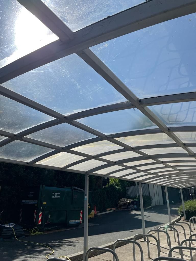 Bike shelter with a transparent roof, on a sunny day.