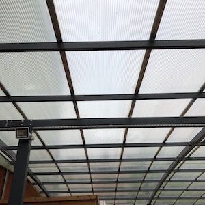 Overhead view of a clear corrugated plastic roof supported by a dark gray metal frame.