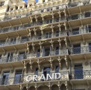 Grand hotel facade, cream-colored, multiple balconies with black ironwork, 