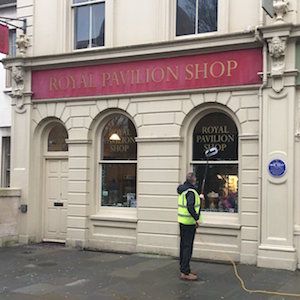 Window Cleaning Operator cleaning outside windows of Brighton's royal pavilion shop