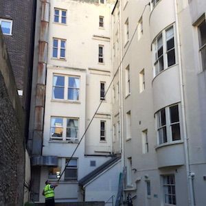 Man using telescopic window cleaning method on high rise residential building