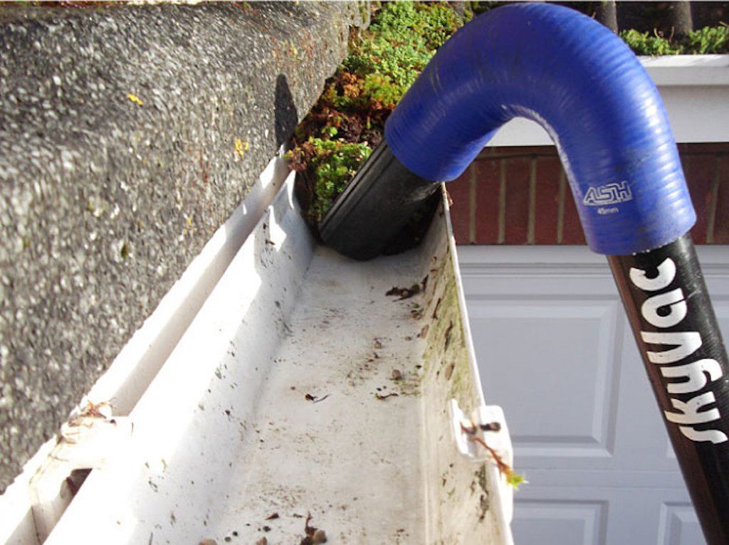 A gutter being cleaned with a blue vacuum attachment allowing for fixed price gutter cleaning