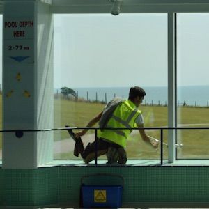 Man cleaning inside of windows with Traditional window cleaning squeegee technique