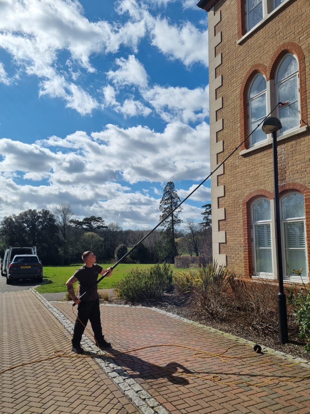 Man using telescopic pole with pure water residential window cleaning