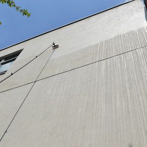 Light gray building exterior with water streaks and a blue sky background.