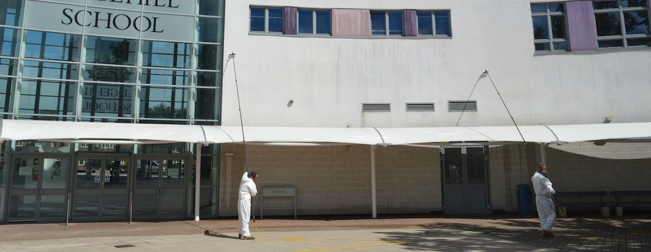 Astound Cleaning Group operatives soft-washing the render of a commercial school building in Sussex — professional commercial render cleaning