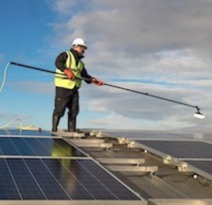 Astound Cleaning Group Staff cleaning solar panels on the roof of a building.