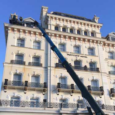 Mercure Hotel with a blue crane reaching towards its roof on a sunny day.