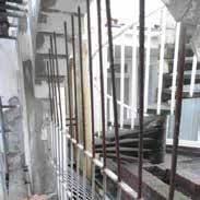 Construction site with iron rods, a staircase, and unfinished walls.
