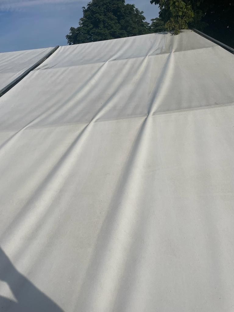 White tent roof with visible seams, slightly wrinkled in sunlight.