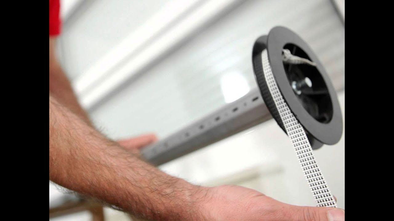 Pessoa a substituir fita da persiana cinza.