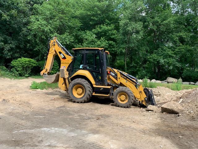 A yellow backhoe performing excavation services.