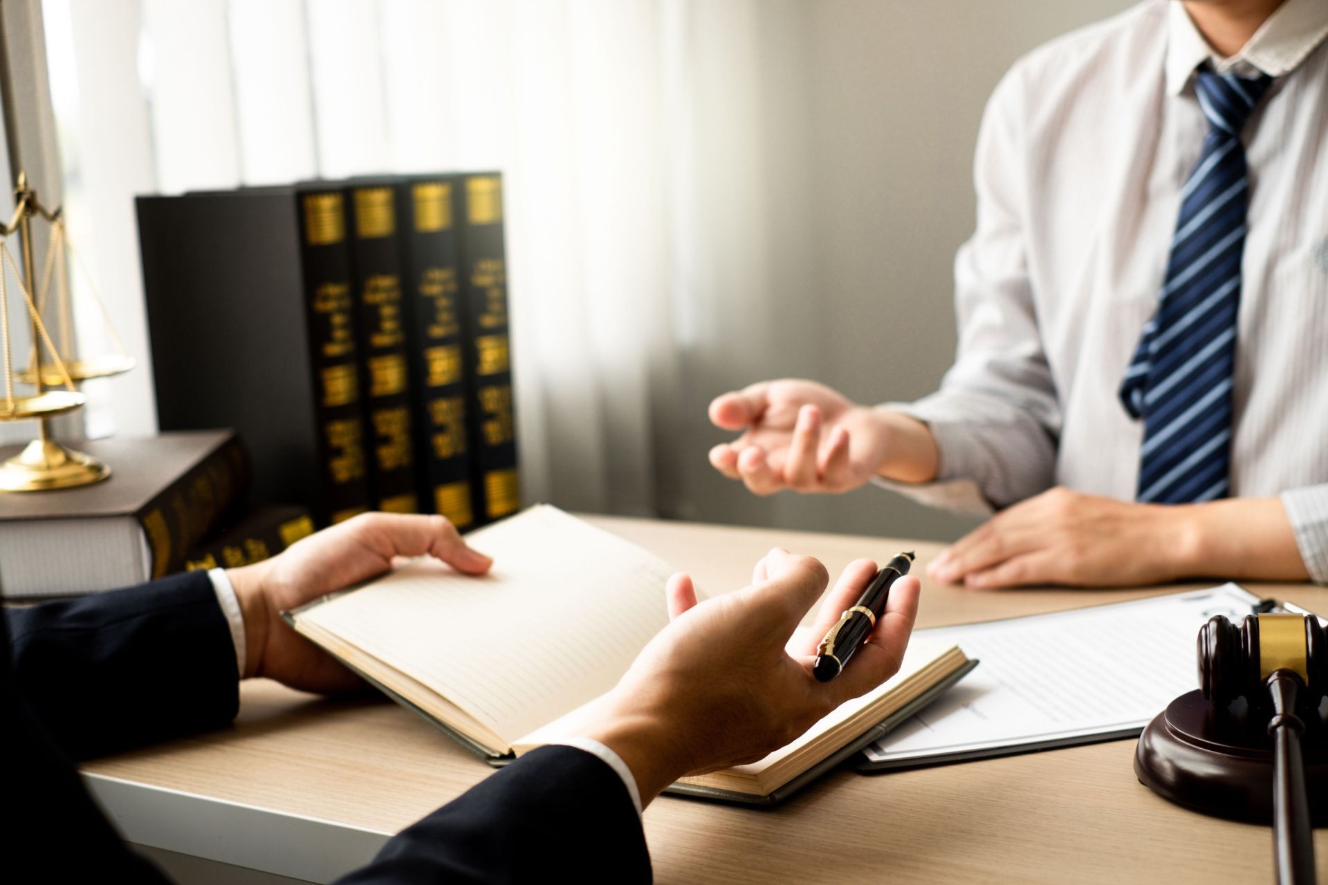 a man in a suit and tie is sitting at a desk talking to another man .