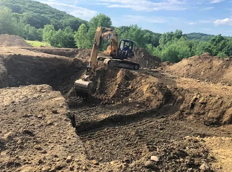 A bulldozer is digging a hole in the dirt in a field.