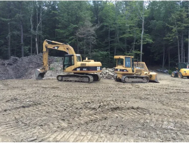 A cat excavator and a bulldozer are parked in a dirt field