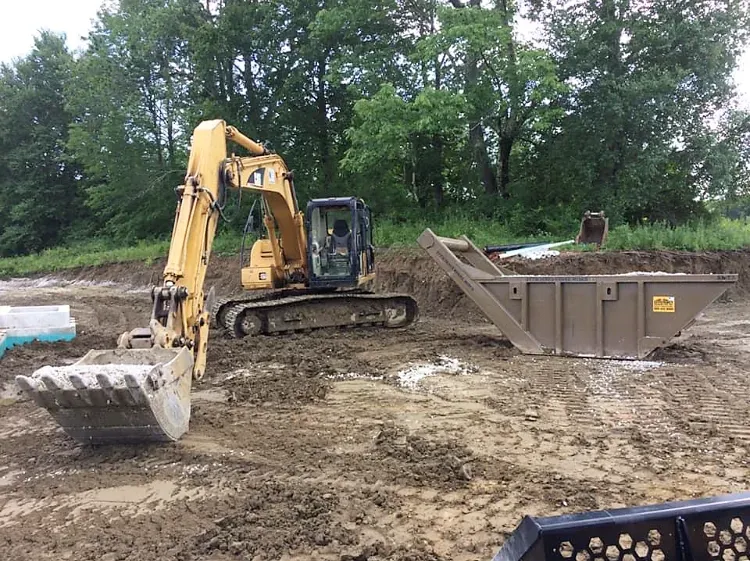 A yellow excavator is moving dirt in a dirt field.