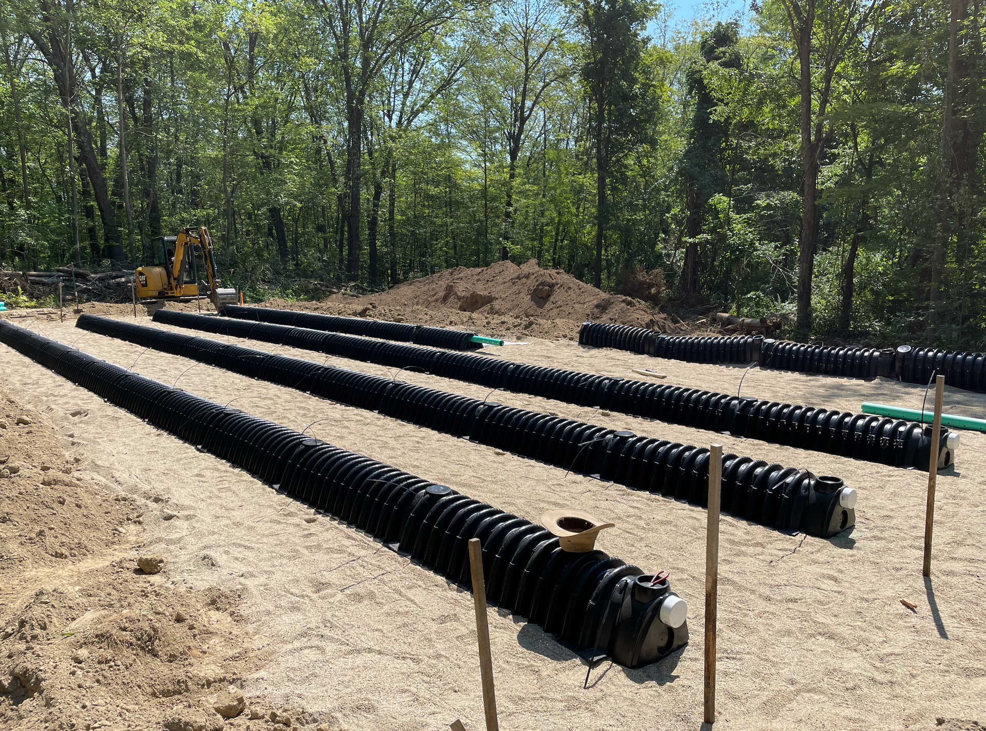 A row of black pipes sitting on top of a dirt field.