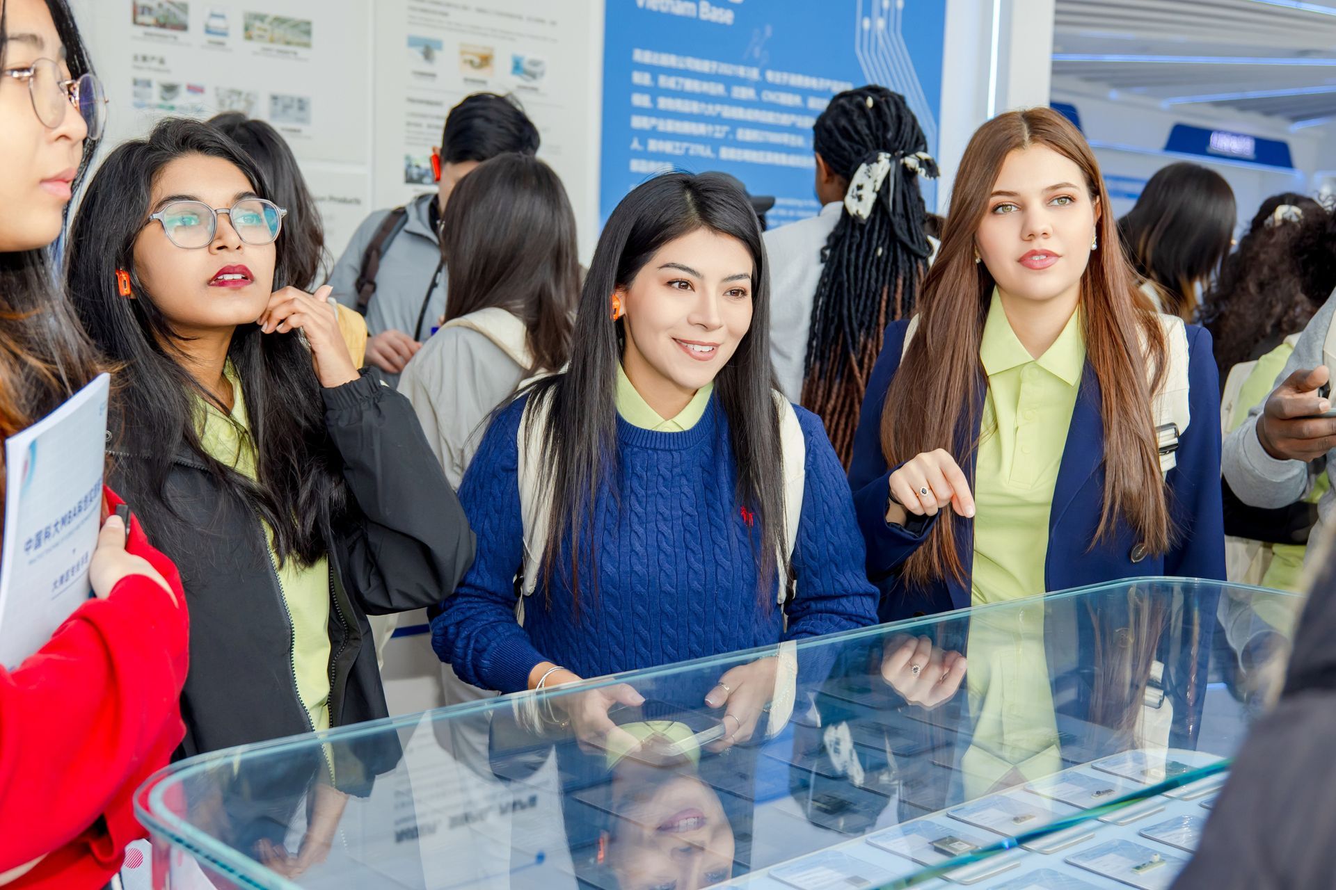 Students at an exhibit, looking at items in a glass case. Some are wearing blue and yellow shirts.