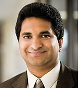 Smiling South Asian man in a suit and tie.