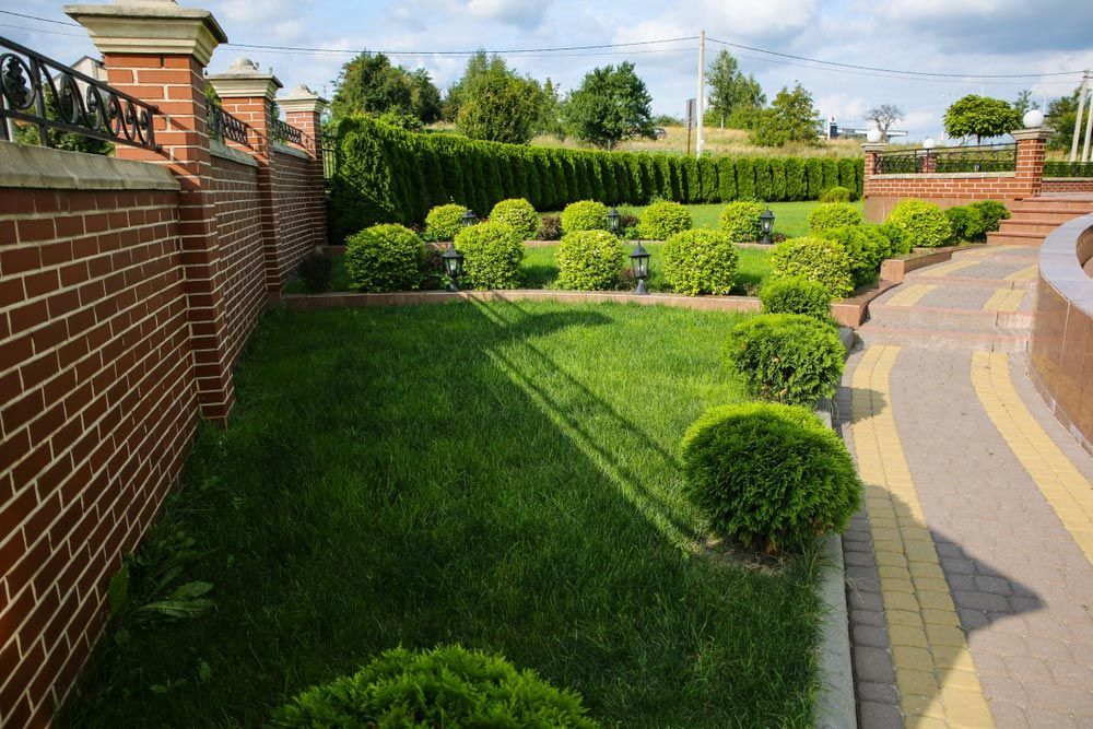 Brick Wall Surrounds A Lush Green Garden — J & G Services in Bungadoo, QLD
