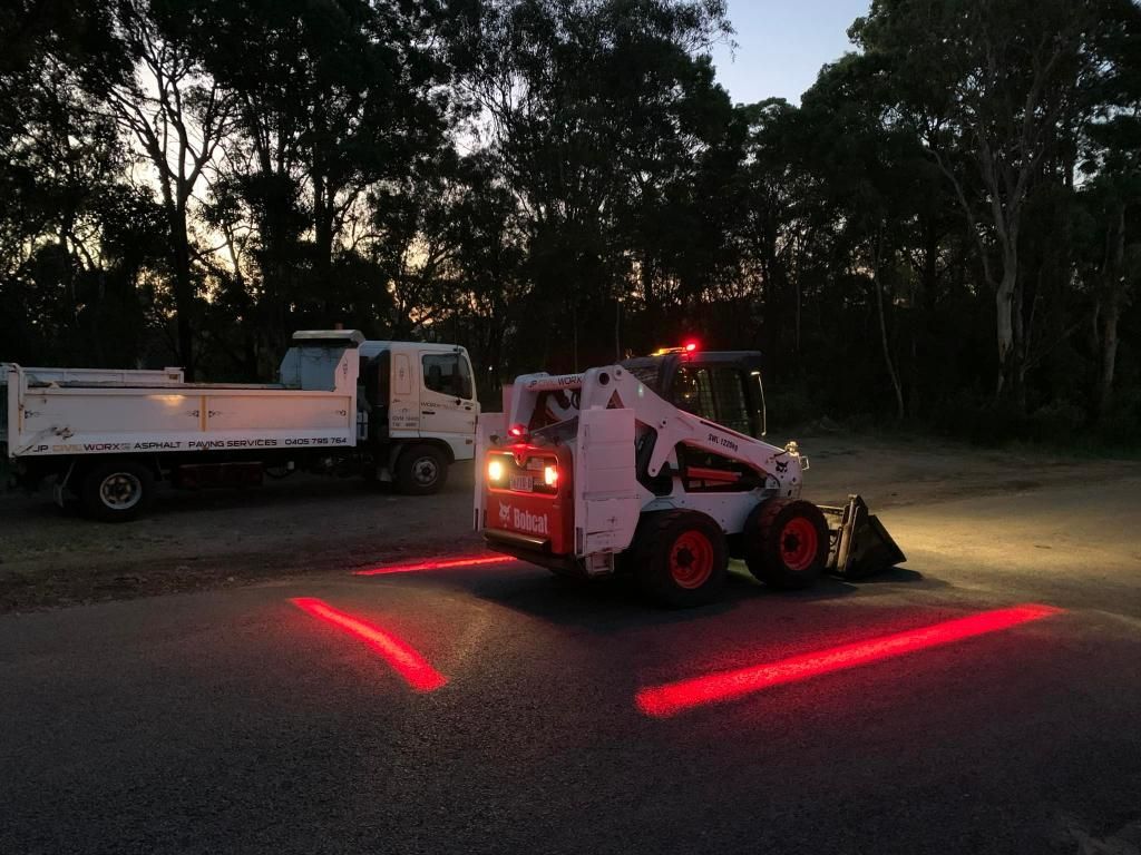 Bobcat Tractor is Driving Down a Road at Night — JP Civilworx Pty Ltd in Newcastle, NSW