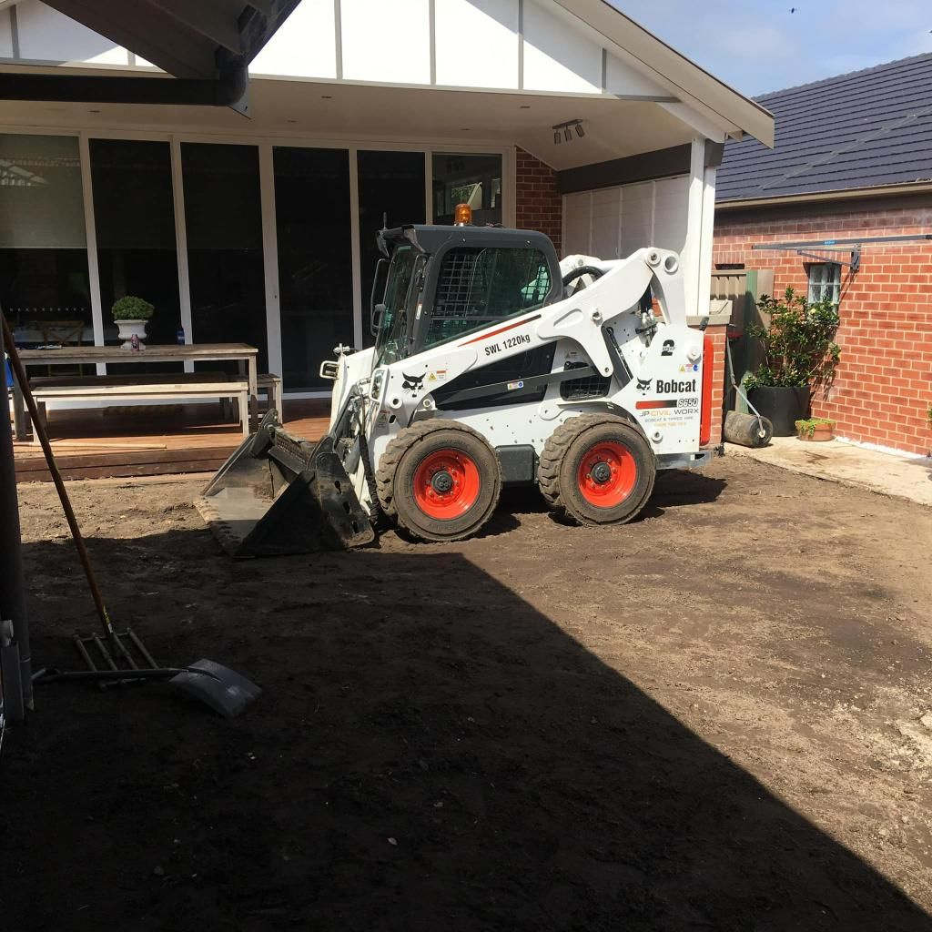 Bobcat Tractor is Parked in Front of a Brick House — JP Civilworx Pty Ltd in Lake Macquarie, NSW