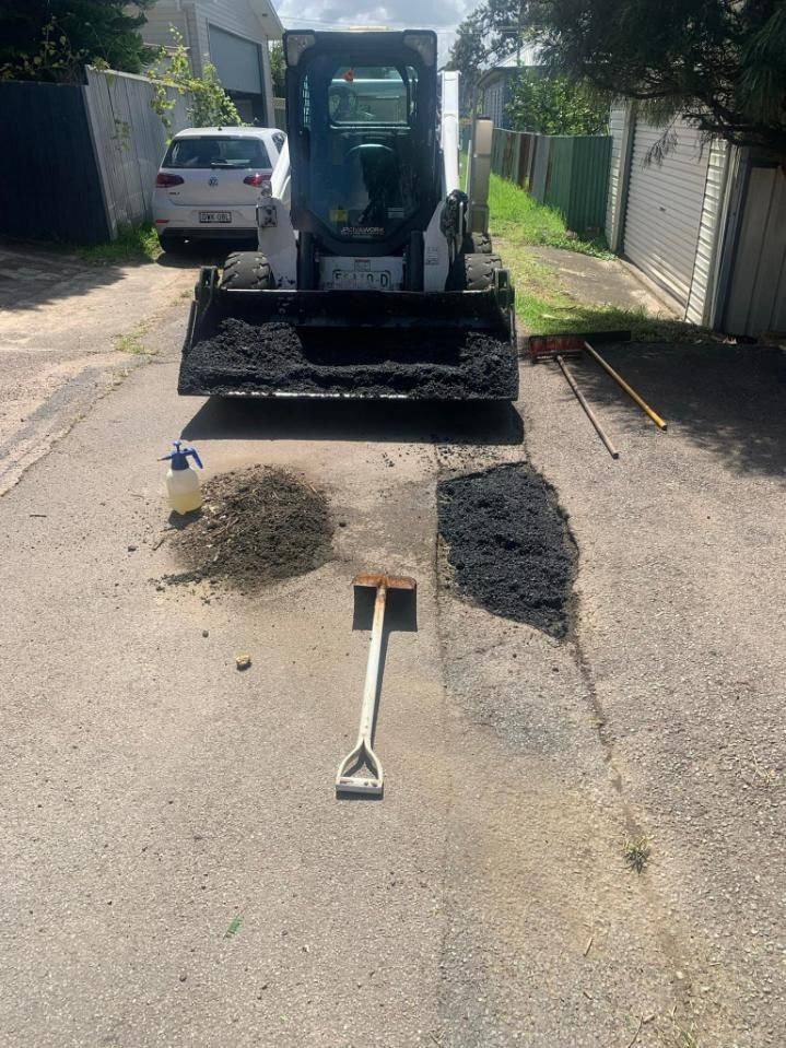 A bulldozer is sitting on the side of a road next to a shovel — JP Civilworx Pty Ltd in Eraring, NSW