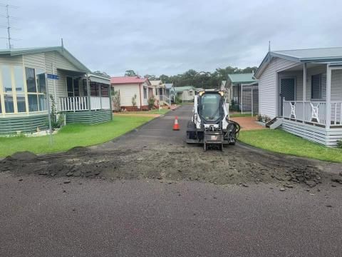 Bulldozer is Driving Down a Dirt Road in a Mobile Home Park — JP Civilworx Pty Ltd in Newcastle, NSW