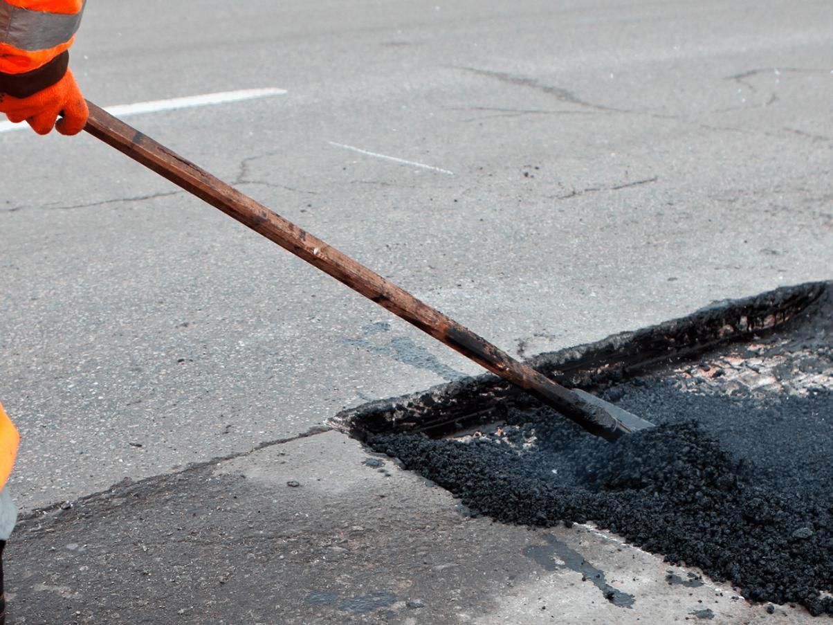 Person is Spreading Asphalt on a Road With a Shovel — JP Civilworx Pty Ltd in Maitland, NSW