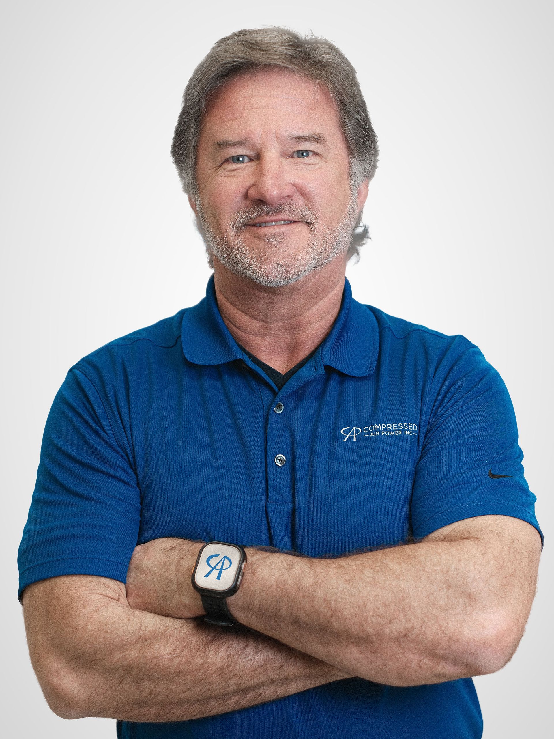 A man with a beard is wearing a blue shirt and smiling for the camera.