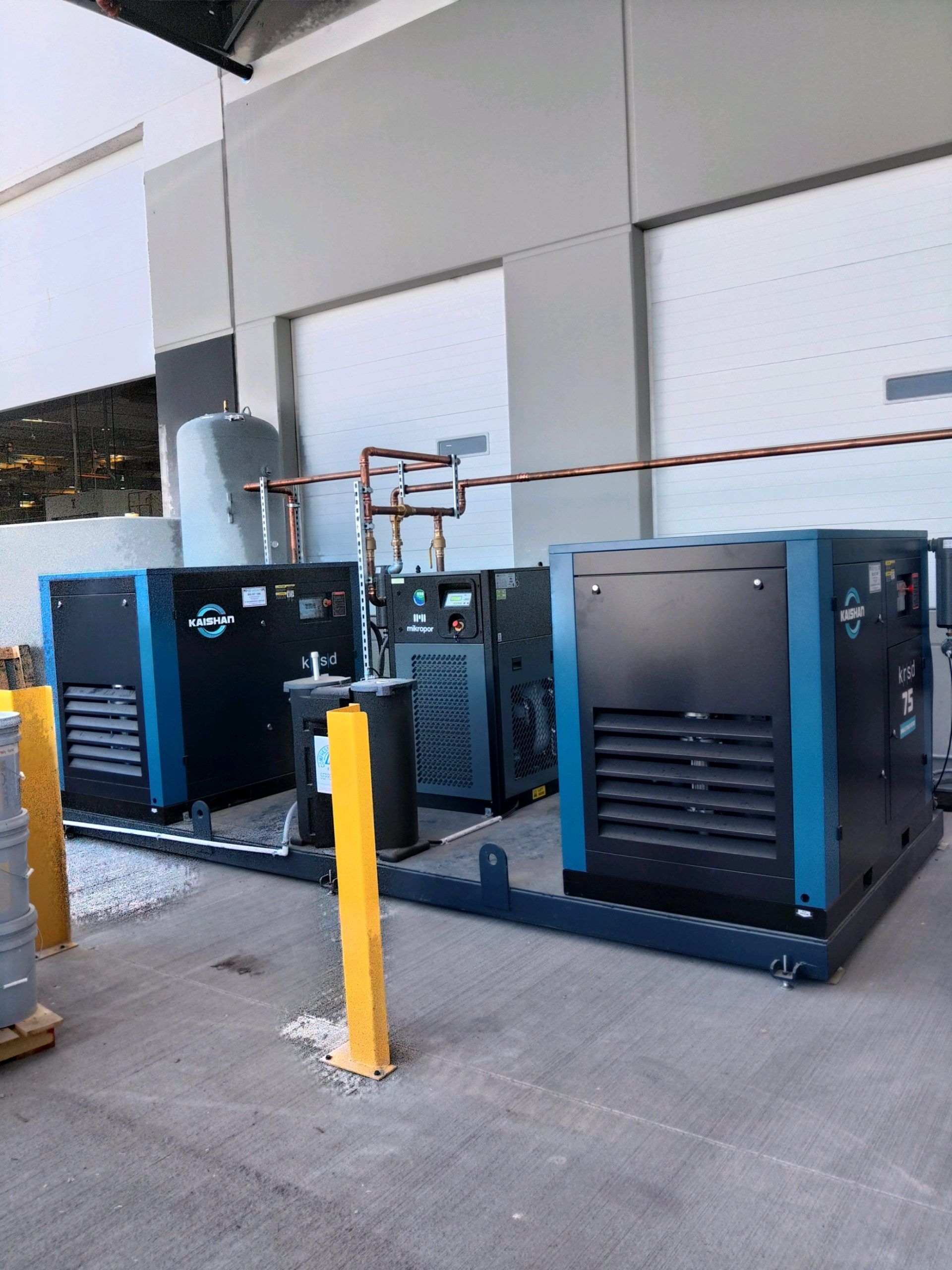 A row of air compressors are parked in front of a building