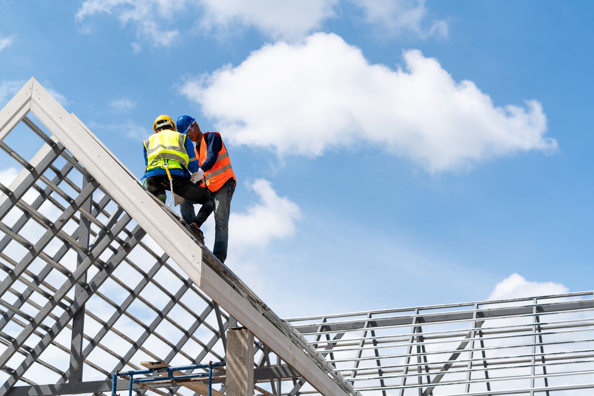 Two construction workers are working on the roof of a building under construction.