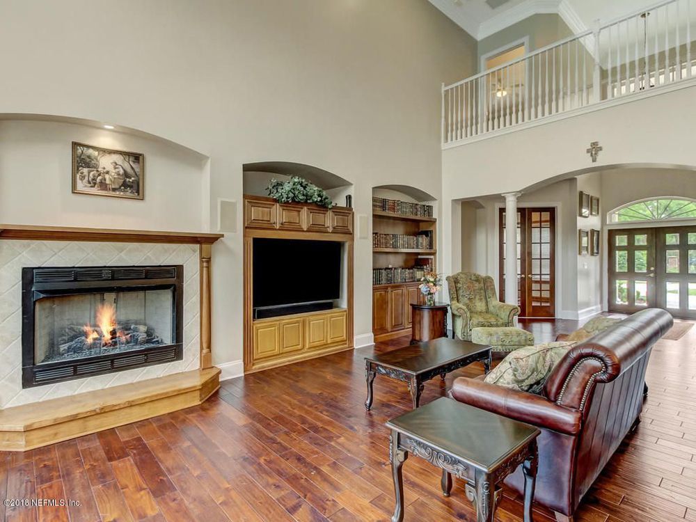 Living room with fireplace, TV, built-ins, and leather sofa, with hardwood floors.
