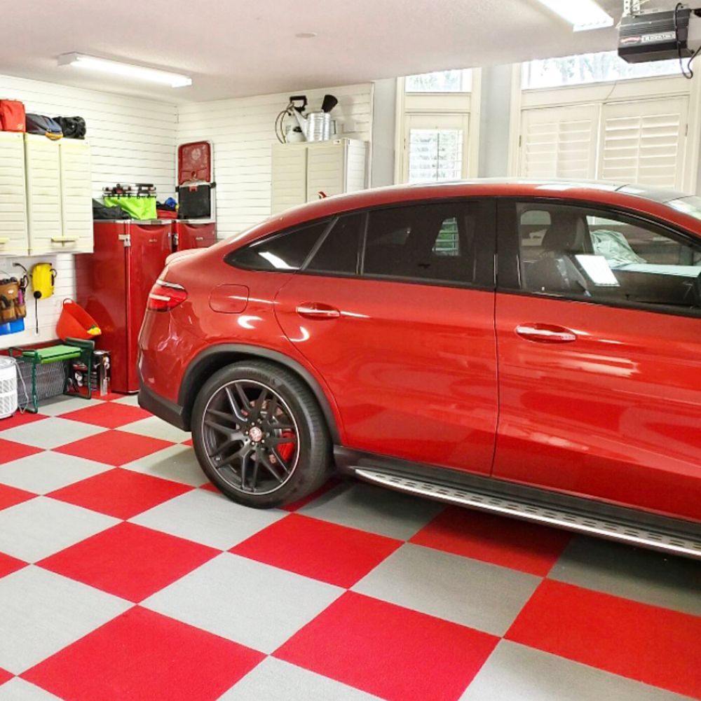 Red car parked in a garage with red and gray checkered floor.