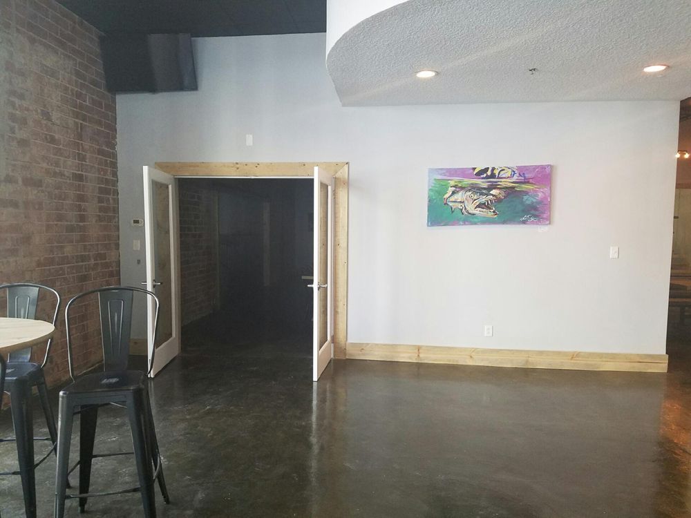 Interior with door, artwork, brick wall, and black chairs.