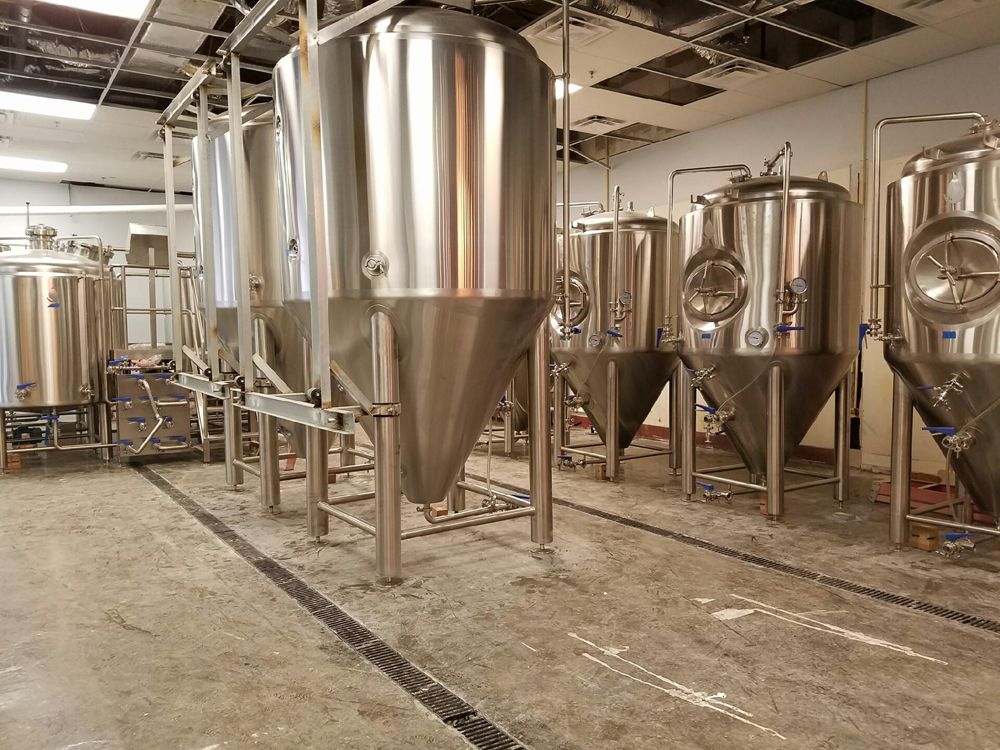 Stainless steel beer fermentation tanks inside a brewery.
